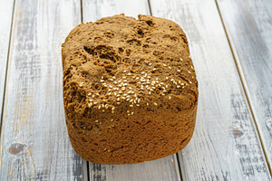 Whole grain bread loaf with sesame seeds and flax seeds on a rustic wooden tabl, a Food & Drink Photo by Eugene_Photo