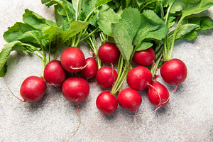 Fresh red radishes with green leaves on grey background, a Food & Drink Photo by Olena Rudo