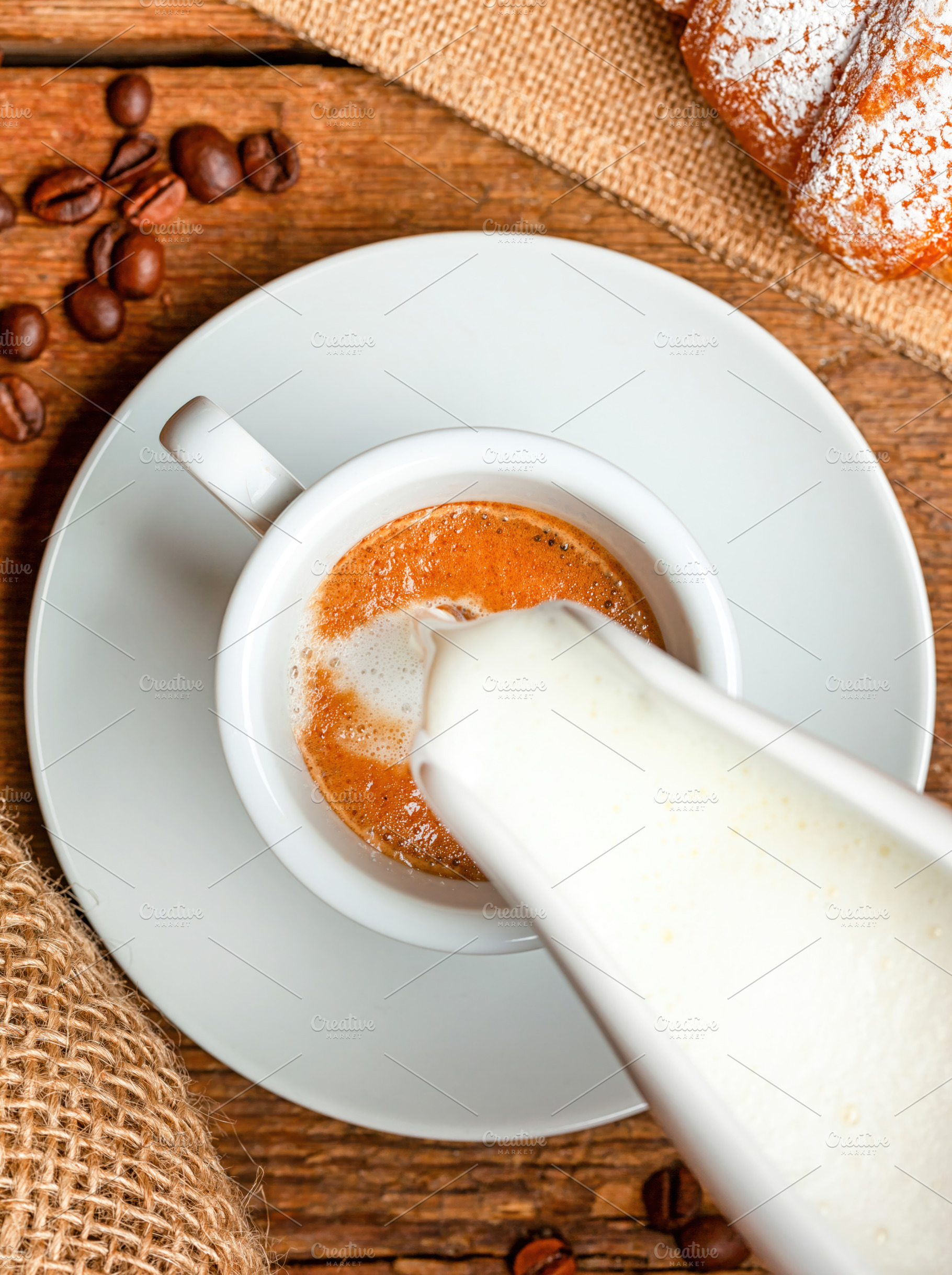 Barista pouring milk into a cup of coffee creating macchiato on wooden table wi, a Food & Drink Photo by Antonio Gravante Market