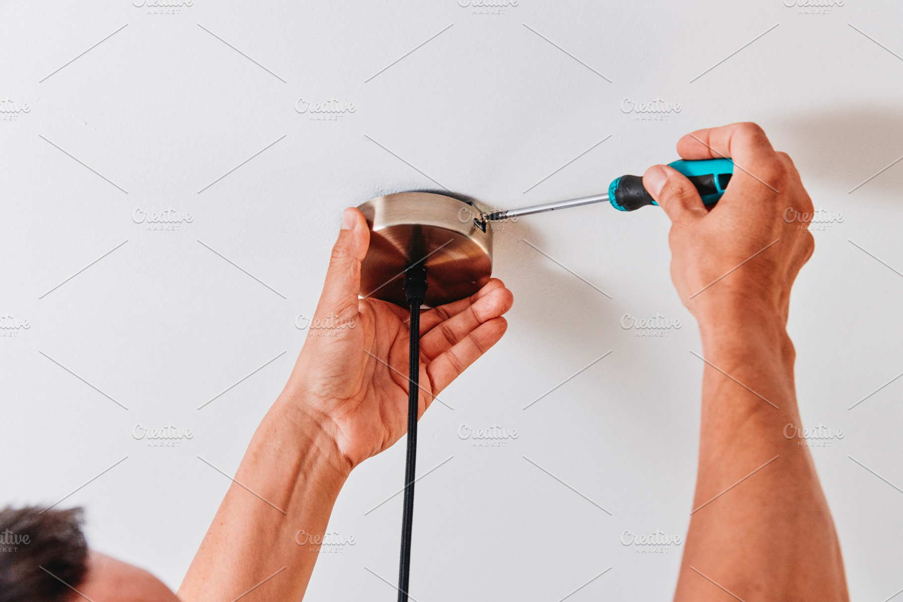 securing a ceiling light canopy with a screwdriver, a Photo by Nito