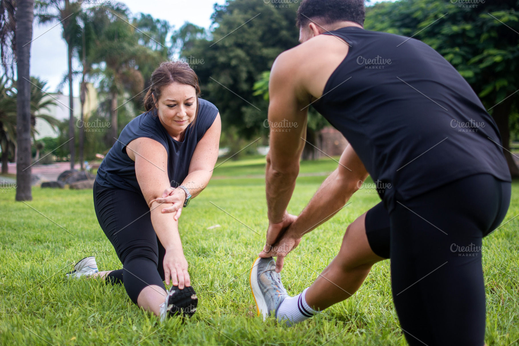 Man and woman stretching their legs together during outdoor workout, a Photo by etorres69
