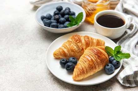 Delicious french breakfast with croissants, coffee, honey and fr