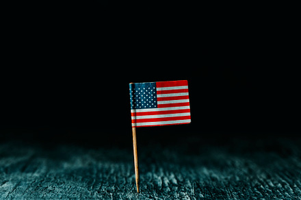 American flag standing on a dark wooden surface, a Photo by Nito