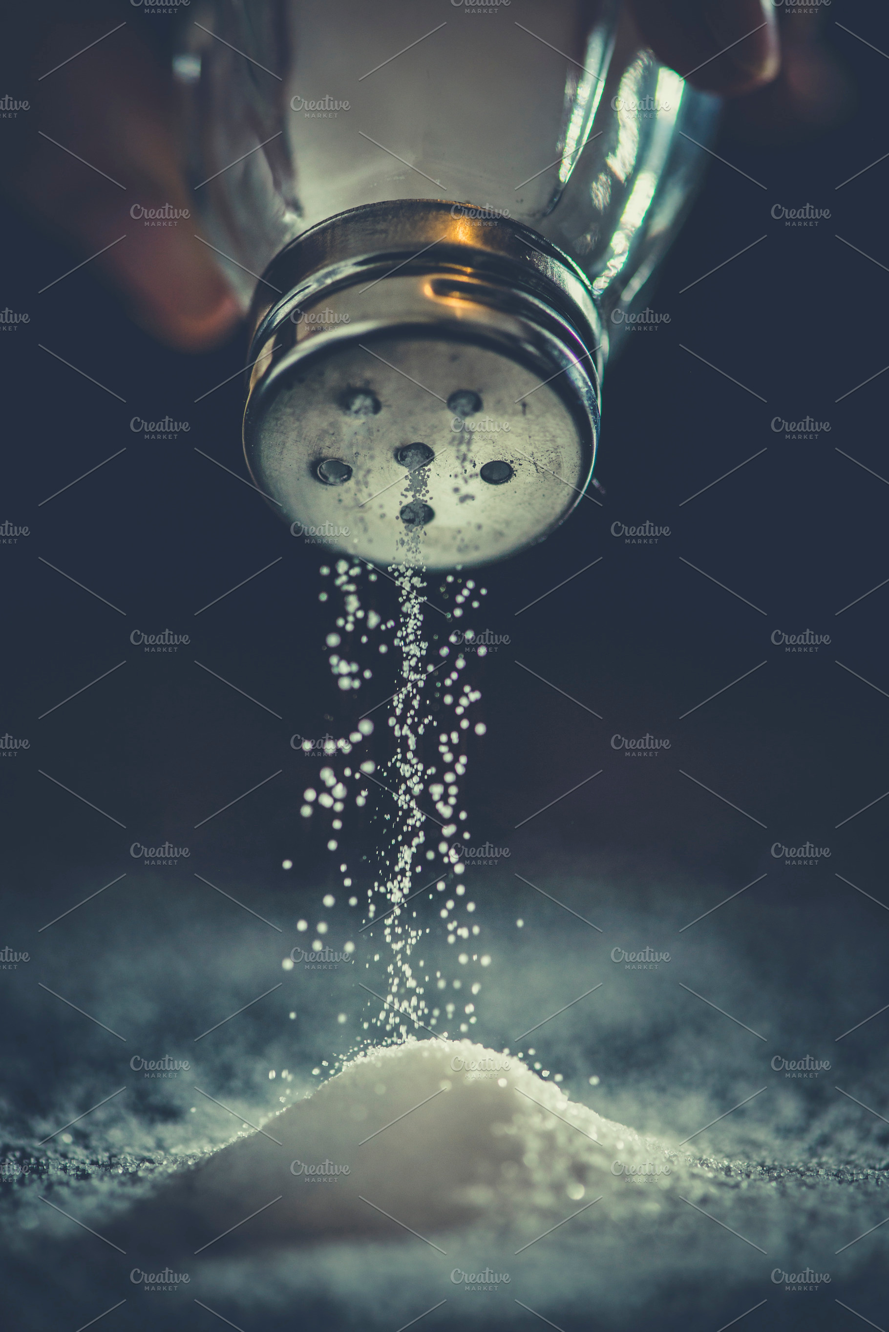 Salt shaker on pile of salt featuring salt, adding, and hand, a Food & Drink Photo by DegImages