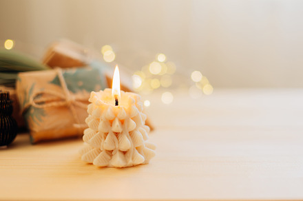 Winter still life. Burning candle shape of tree, gift boxes presents and Christ