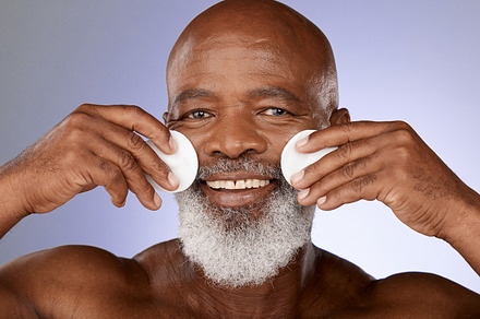 Skincare, facial cotton and senior black man on purple background in studio for beauty, wellness and cosmetics. Luxury spa, dermatology and face portrait of elderly male with pads to cleanse skin, a Photo by Peopleimages.com