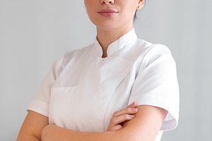 Confident female cosmetologist in lab coat standing at clinic, a Photo by andreonegin market