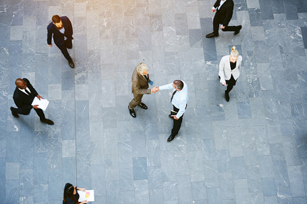 Businessmen shaking hands in crowded office hall, a Business Photo by Stefan & Janni