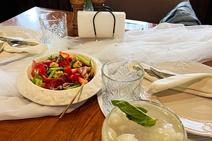 Elegant dining table with salad, cocktail, and decorative floral arrangement, a Photo by AS photostudio