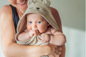 Mother holding her baby wrapped in a, a Person Photo by Elizaveta Galitskaya