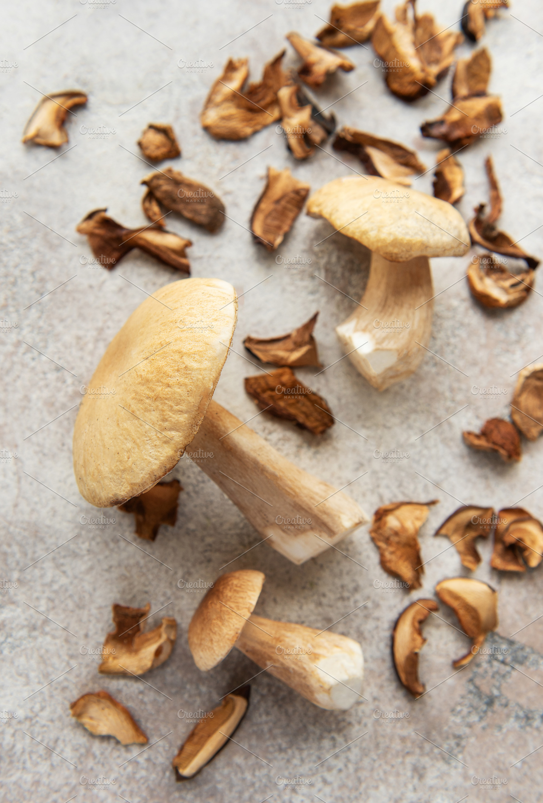 Fresh penny bun mushrooms lying on table with dried slices, a Food & Drink Photo by Olena Rudo