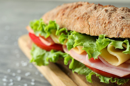 Board with ciabatta sandwich on gray textured table, a Food & Drink Photo by AtlasStudio