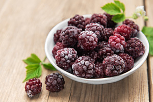 Frozen blackberries in white bowl on wooden background, a Food & Drink Photo by Olena Rudo