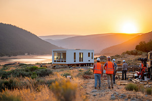 Modular tiny house under construction along serene lakeside at sunset, a Photo by AlyaAnd