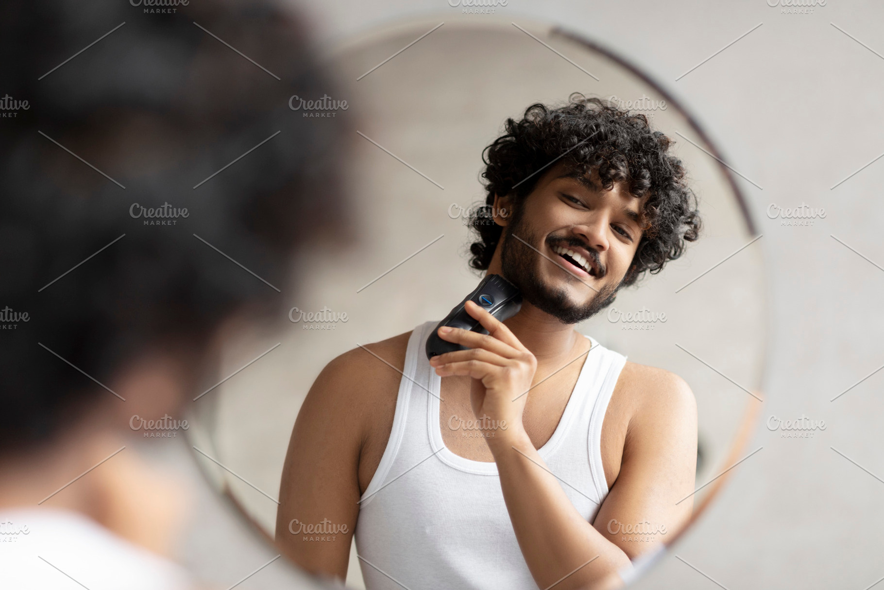 Grooming concept. Handsome young indian man looking at mirror and shaving beard, a Person Photo by Prostock-Studio