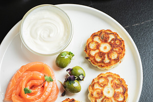 Savory Syrniki with Smoked Salmon, Olives and Sour Cream on White Plate
