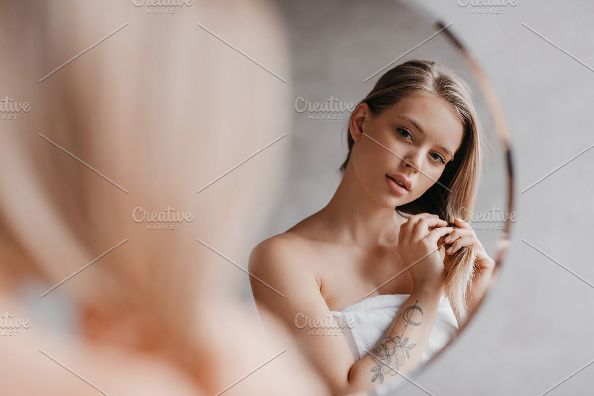 Natural beauty. Pretty young lady touching her soft hair, standing near mirror, a Photo by Prostock-Studio (Photo 2 of 3)