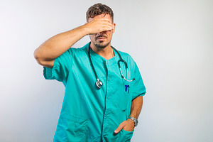 Doctor Covering Eyes with One Hand, a Person Photo by karrastock