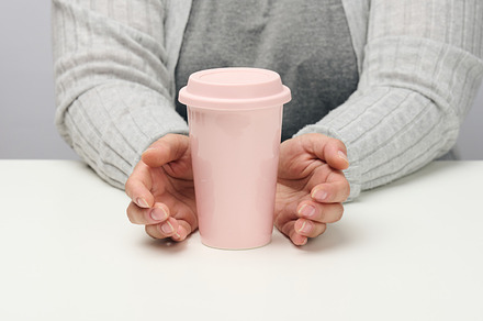 woman in gray clothes holds a pink ceramic cup, woman sits at a, a Food & Drink Photo by ndanko