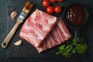 Raw meat. Raw pork ribs from the back with meat on a black background. backgrou, a Food & Drink Photo by Budarinphoto