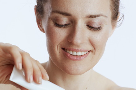 happy modern female with hand cream on white, a Beauty & Fashion Photo by Alliance Images