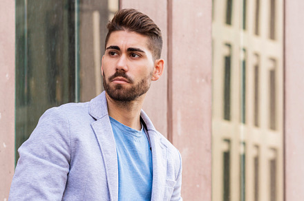 Portrait of outgoing bearded male holding a mobile while looking away outdoor, a Person Photo by RF Images