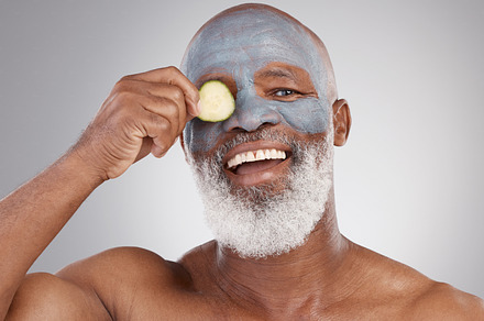 Facial mask, cucumber and black man with smile in portrait, beauty and skincare isolated on studio background. Happy senior male, cosmetic care and healthy skin, anti aging cosmetics routine for face, a Photo by Peopleimages.com