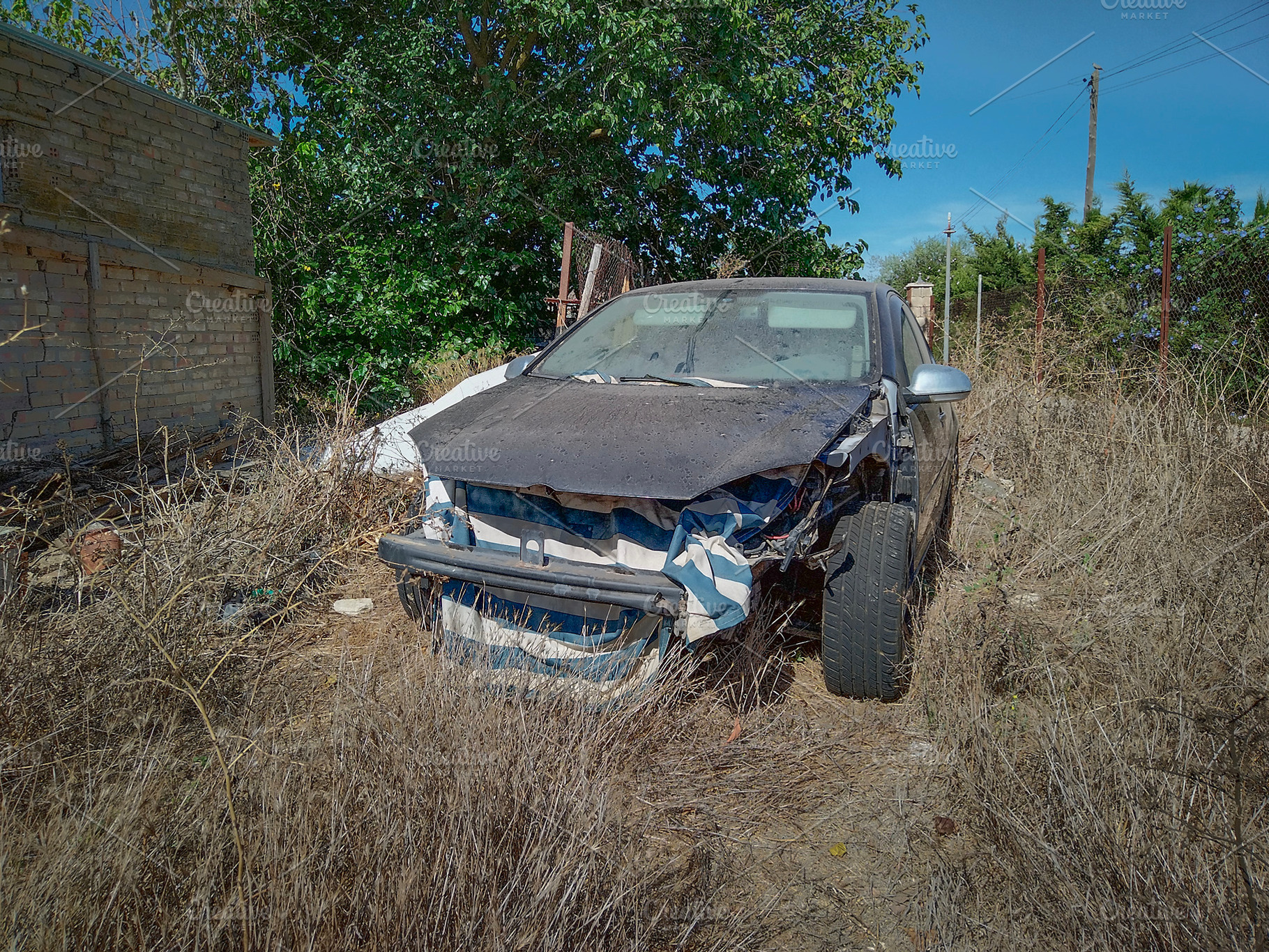 Abandoned crashed car on dry grass, a Transportation Photo by DanFLCreativo