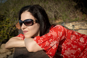 Close-up of a woman in a red floral dress and sunglasses resting, a Person Photo by Imaginarium
