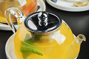 Fruit tea with mango and mint in a glass teapot on the table, a Food & Drink Photo by Budarinphoto