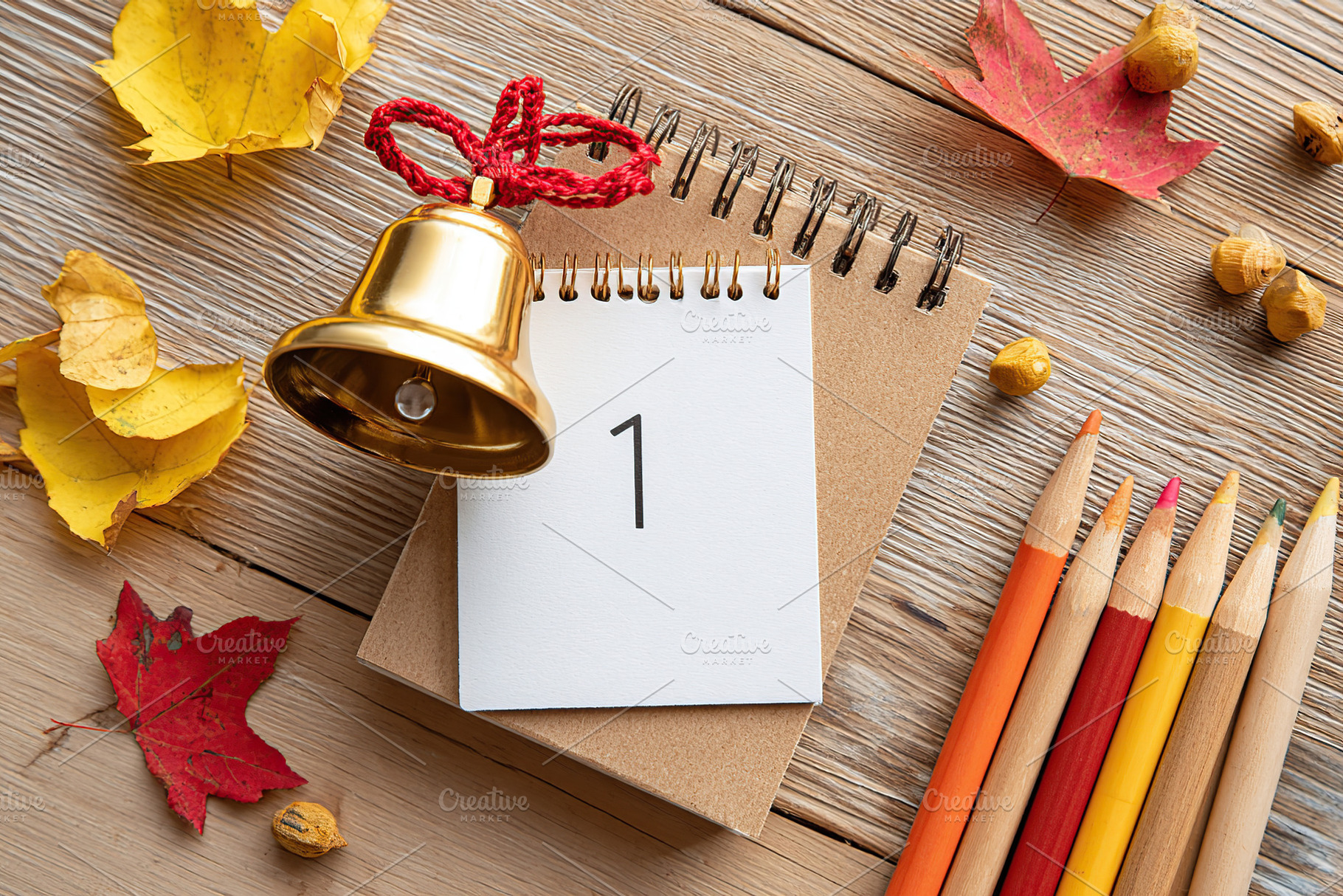 Autumn decorations with a calendar, bell, and colored pencils on a wooden table, a Photo by AlyaAnd