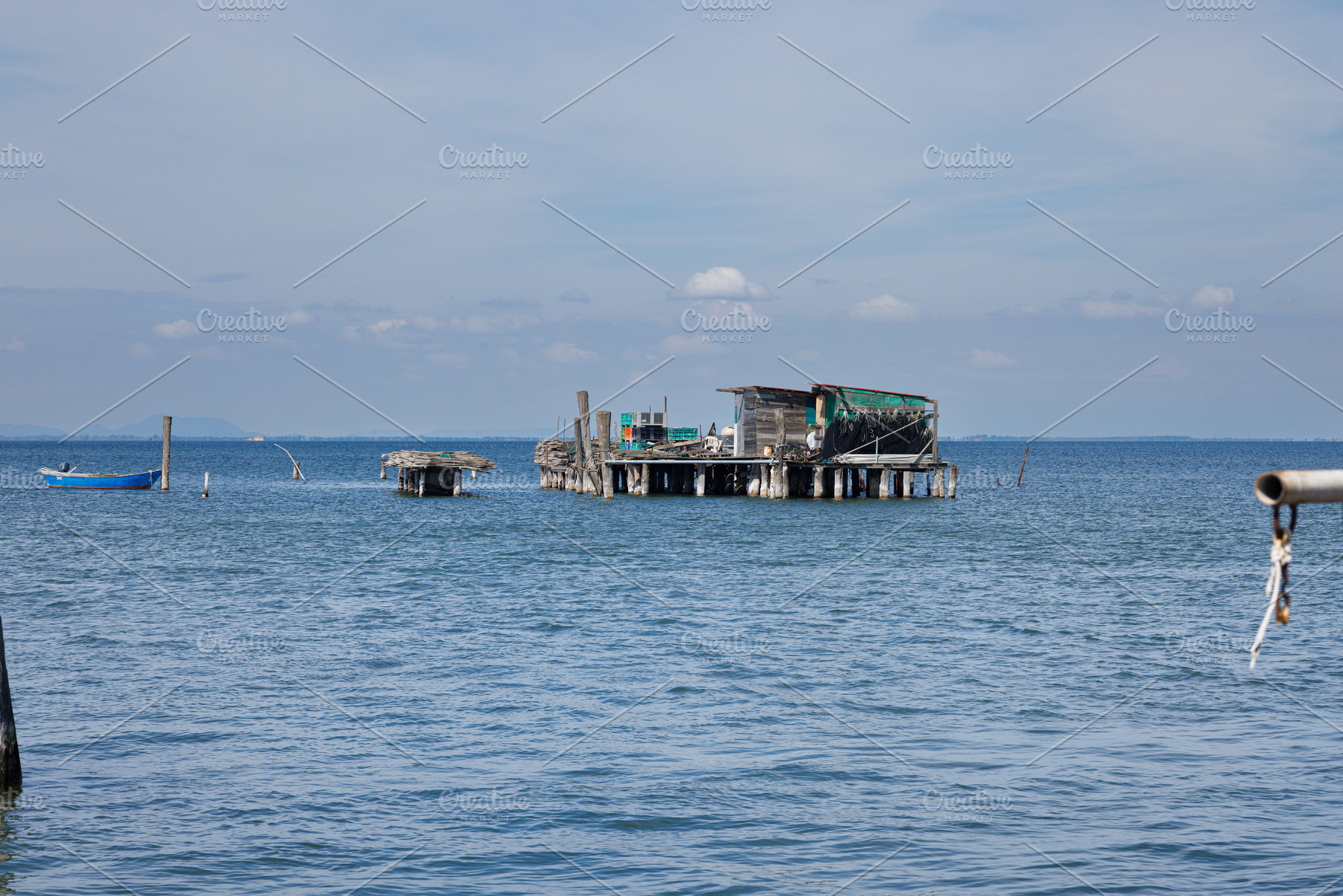 A rustic wooden stilt house and boat with fishing nets, an Architecture Photo by Bepslabor