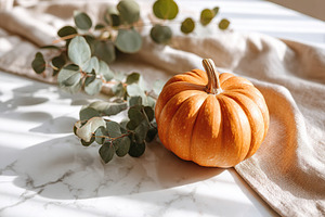 Autumn decor featuring a small pumpkin and eucalyptus on a marble table, a Holiday Photo by AlyaAnd