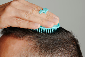 man combs his hair with a round scalp brush, a Photo by Nito