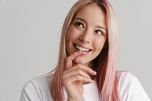 Young woman with pink hair smiling and looking aside