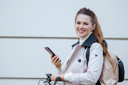 smiling stylish woman using phone app outdoors on city street, a Person Photo by Alliance Images