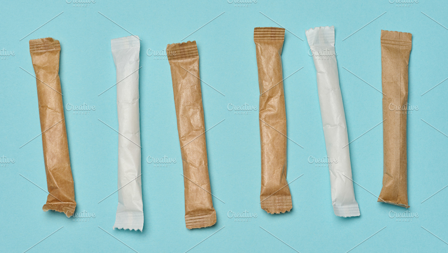 White and brown paper sticks with sugar, arranged in a row on a, a Food & Drink Photo by ndanko