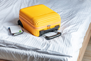 Orange suitcase on hotel bed welcoming travelers arrival, a Holiday Photo by Olena Rudo