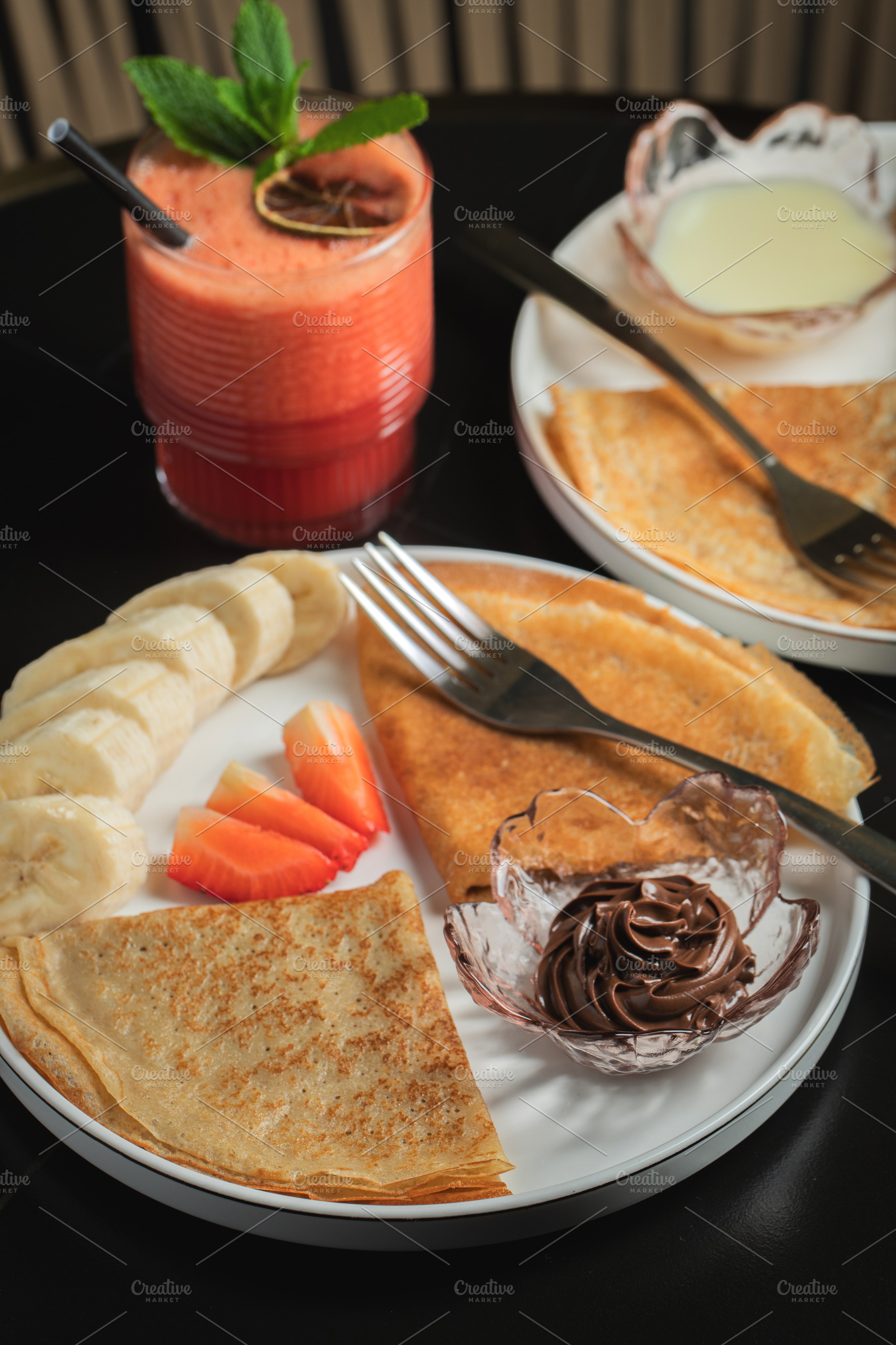 A plate of crepes filled with chocolate spread and topped with banana slices an, a Food & Drink Photo by Budarinphoto
