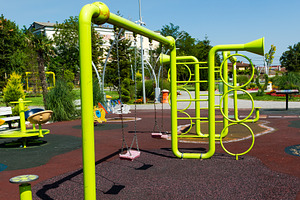 Vibrant green playground structure with swings and climbing elements on a sunny, a Sports & Recreation Photo by Ales Munt