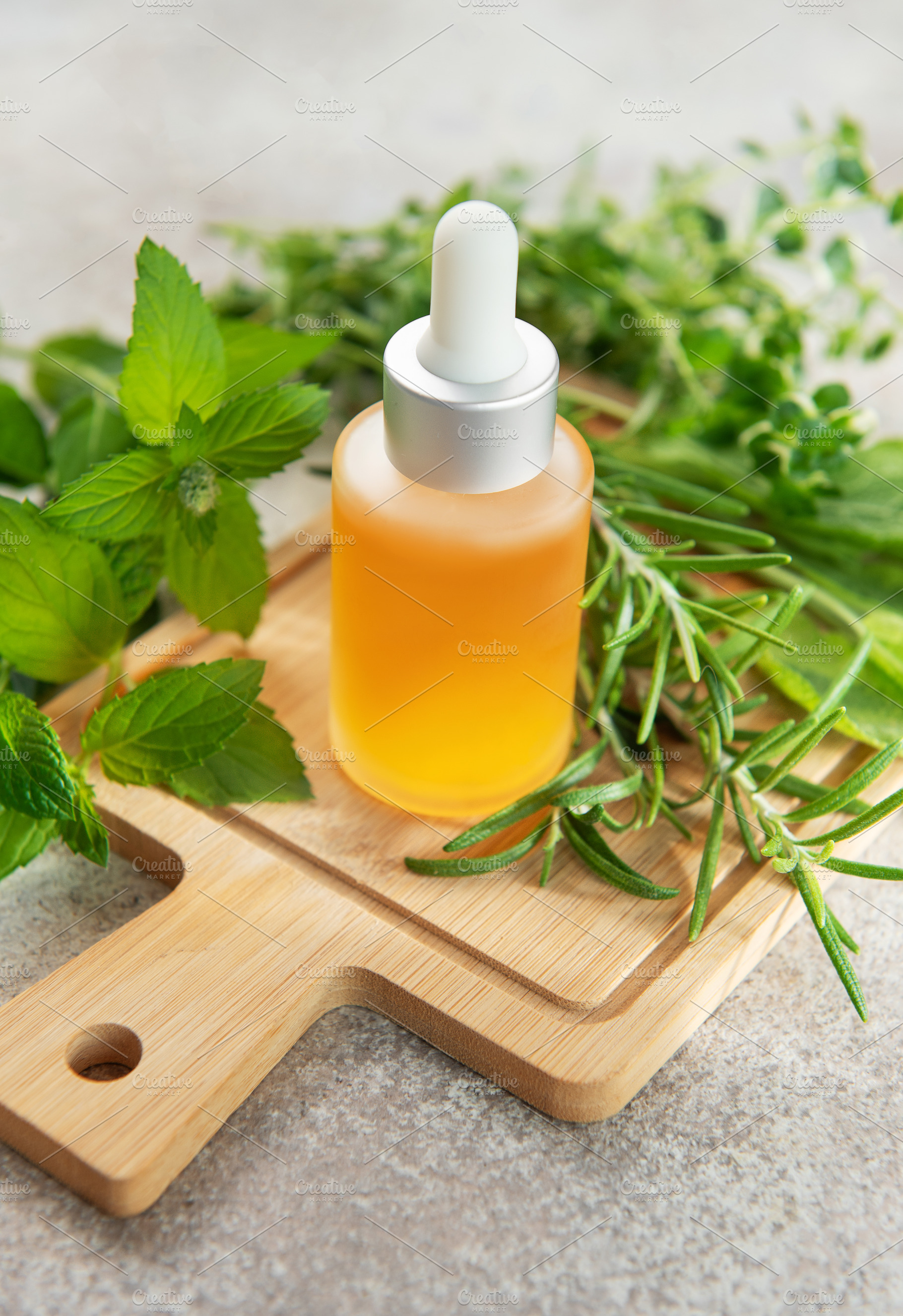 Essential oil bottle with natural herbs and plants on board, a Health & Medical Photo by Olena Rudo