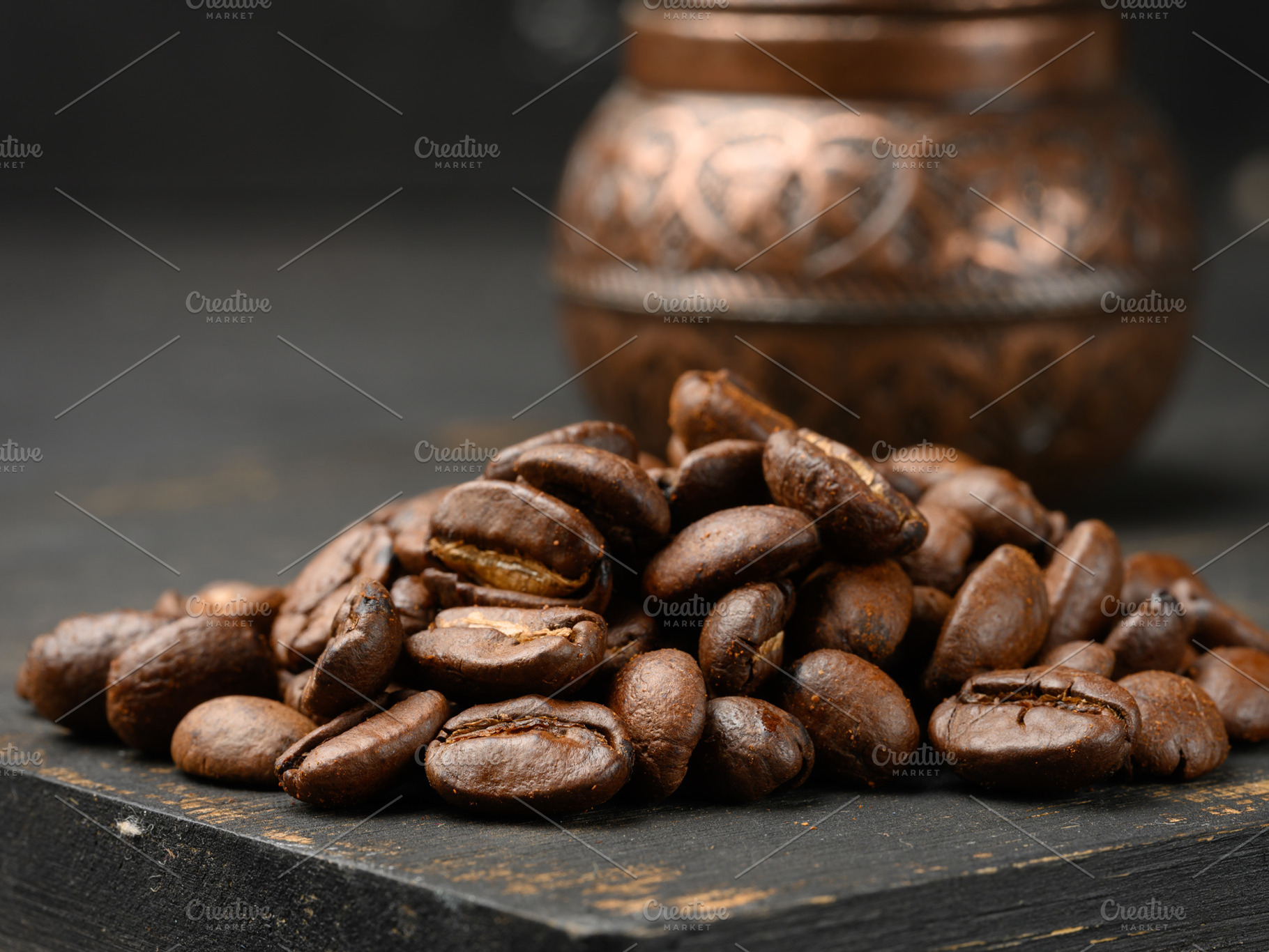 A handful of roasted coffee beans, dark wooden surface, a Food & Drink Photo by ndanko