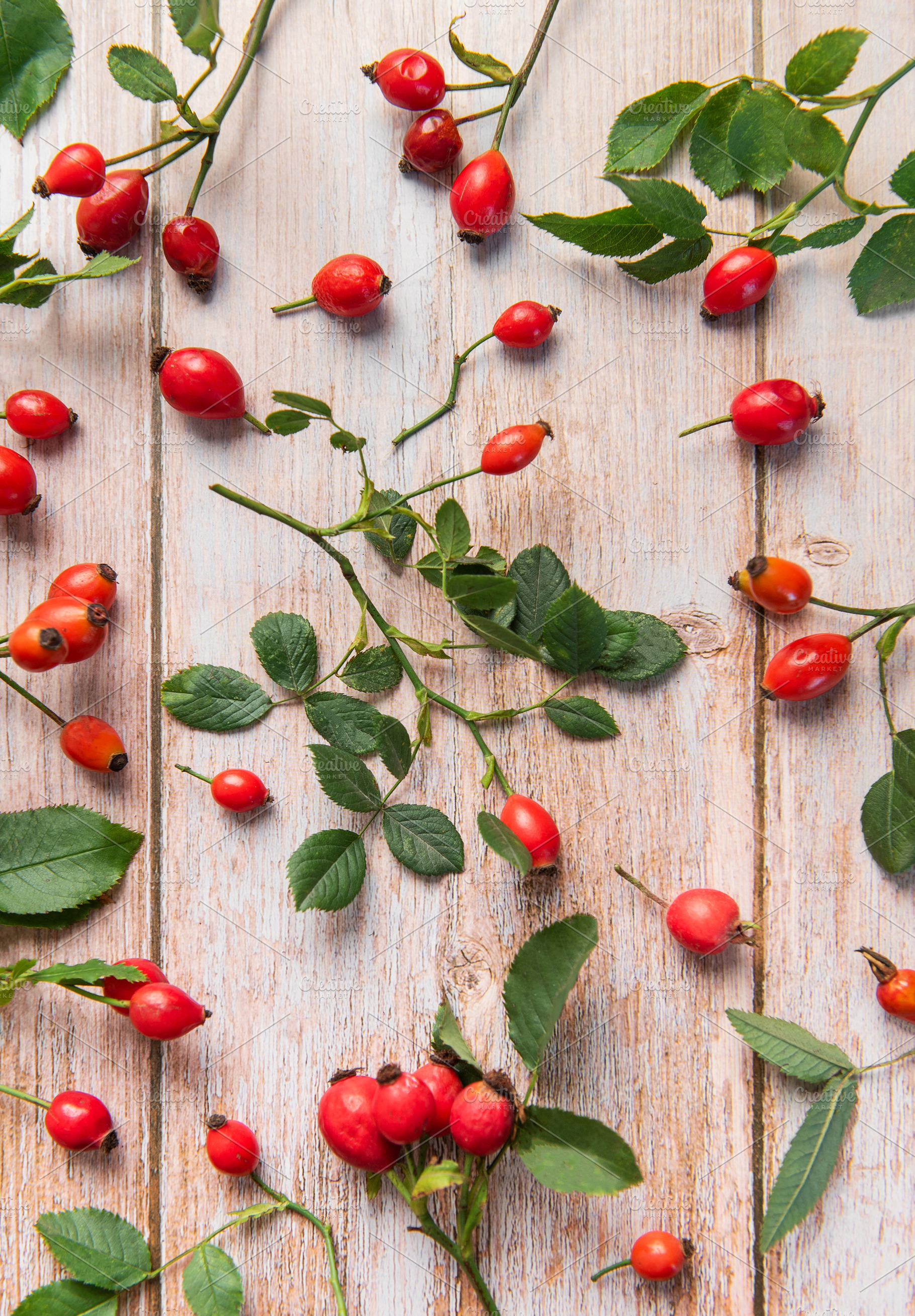 Rosehip berries and leaves arranged on rustic wooden table, a Food & Drink Photo by Olena Rudo