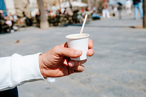 man with an espresso macchiato in a takeaway cup, a Photo by Nito