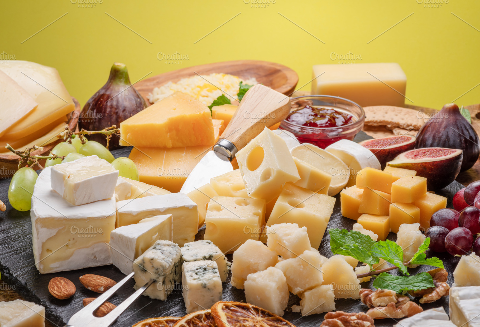 Variety of sliced cheeses with fruits, mint, nuts and cheese cut, a Food & Drink Photo by Volff
