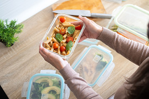 Person holding healthy pasta meal in glass container during meal prep, a Person Photo by etorres69