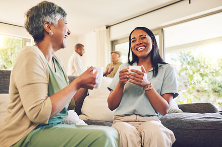 Woman drinking a cup of coffee with her senior mother while laughing, talking and bonding at home. Happy, smile and elderly female person enjoying a cappuccino with her adult daughter in living room., a Photo by Peopleimages.com