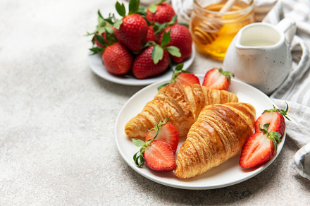 Delicious french croissants with fresh strawberries and honey fo