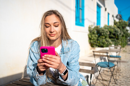 Happy woman using smartphone sitting outdoor cafe in Portugal city, a Person Photo by andreonegin market