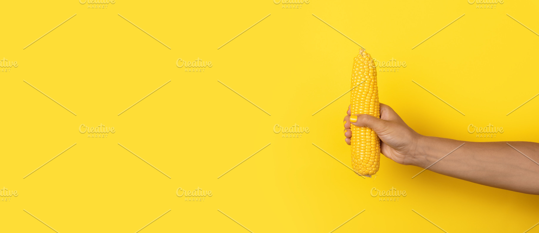 Female hand with yellow nail polish gripping a whole ear of corn, a Food & Drink Photo by Ales Munt